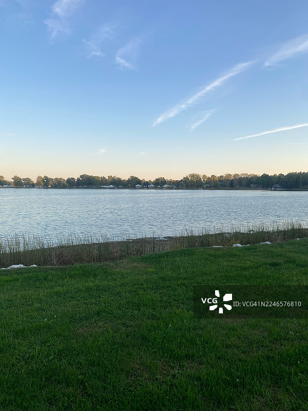 美国奥兰多，前景是绿草如茵，远方有房屋，天空晴朗，一幅宁静湖泊的美景图片素材