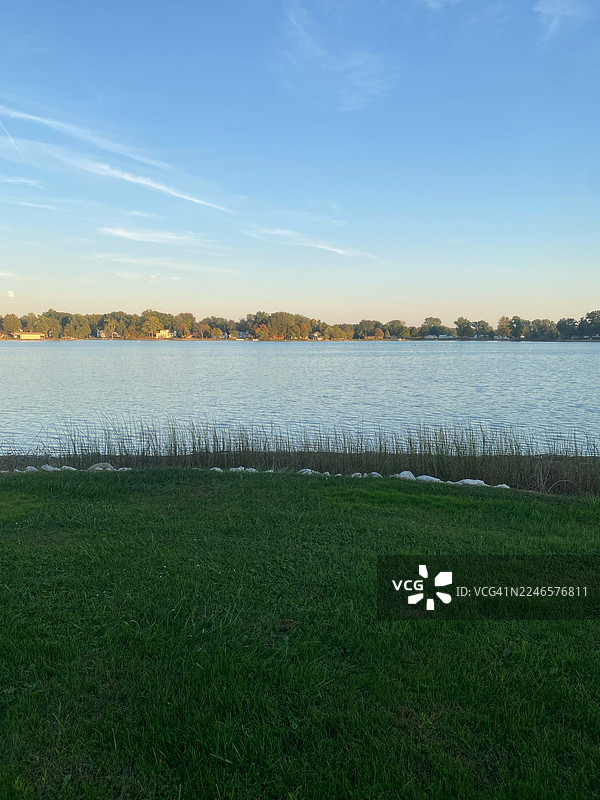 晴朗蓝天下，奥兰（美国）宁静的湖景，绿草与远方海岸线图片素材