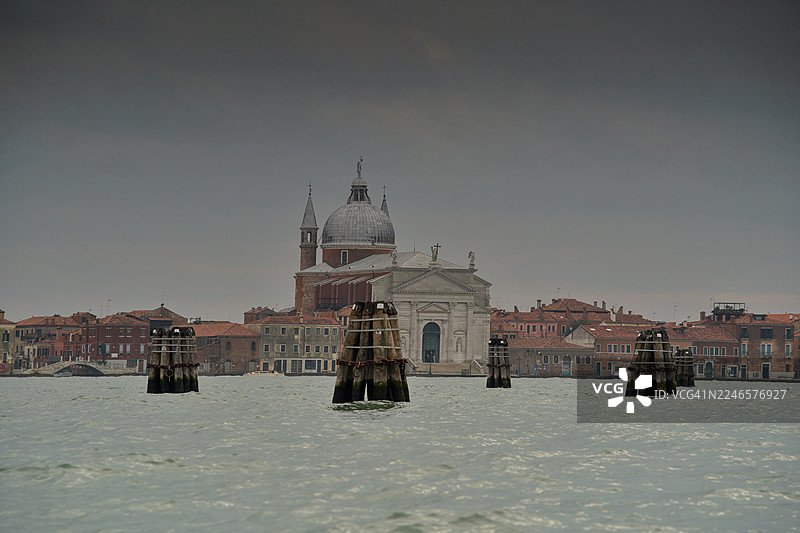 多云天气下威尼斯泻湖上的历史教堂，带有停泊柱，意大利威尼斯图片素材