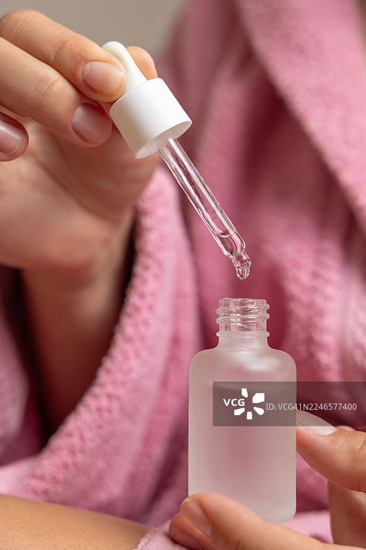 特写镜头：一个人拿着滴管，将液体滴入小瓶中，突出护肤流程图片素材