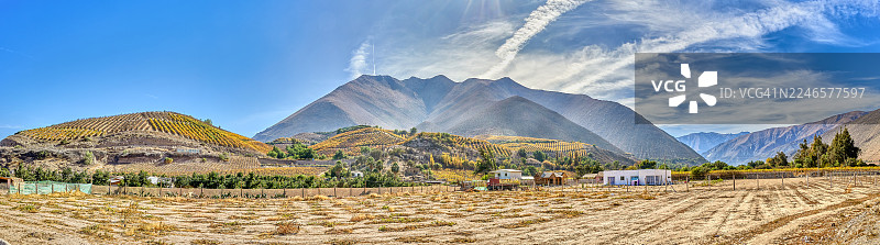 智利埃尔基地区，在明亮的蓝天下，可以看到层叠的梯田葡萄园和远处的山脉，点缀着缕缕白云的壮丽全景。图片素材
