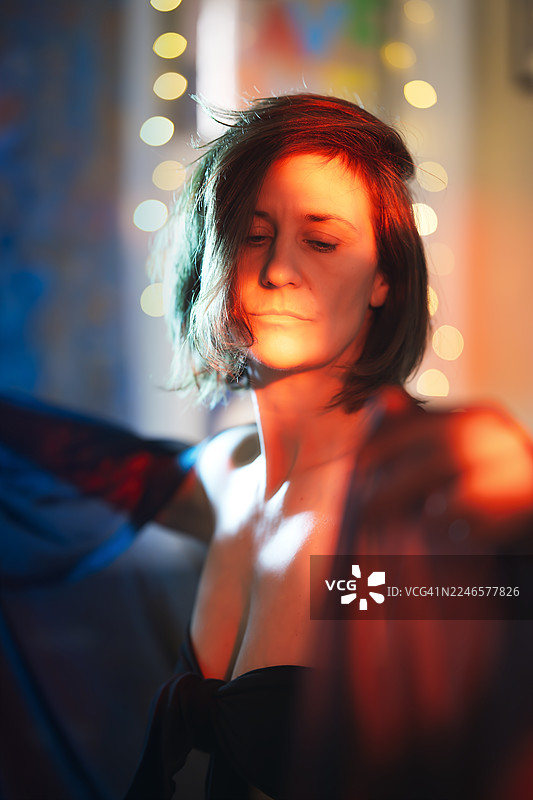 昏暗房间里，一位年轻女子被串灯照亮，营造出梦幻般的内省氛围图片素材