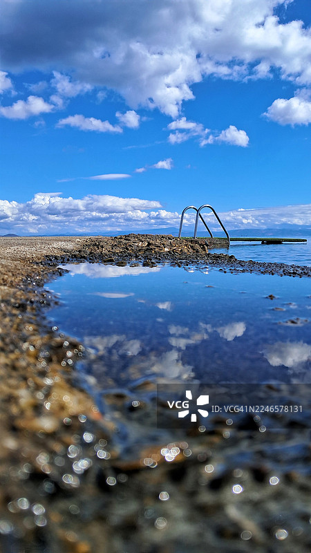 宁静大海与绚丽天空的美景，水坑倒映着云彩，构成一幅宁静如画的风景图片素材
