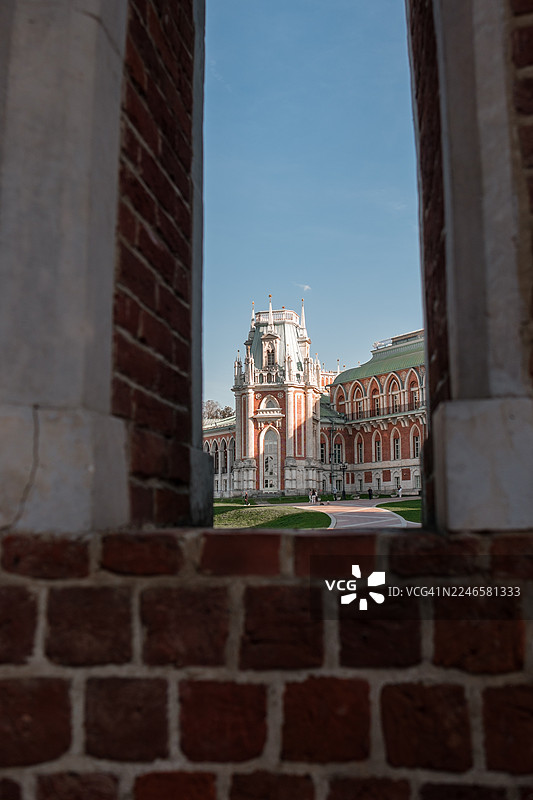 阳光明媚的一天，透过古老的砖砌窗框可以看到一座历史悠久的宫殿图片素材