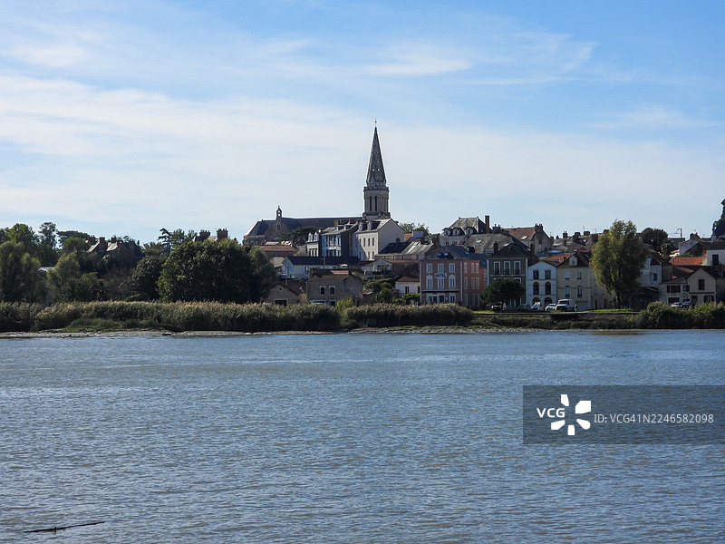 法国，宁静河流旁，蓝天白云下的风景如画小镇，教堂尖顶清晰可见图片素材