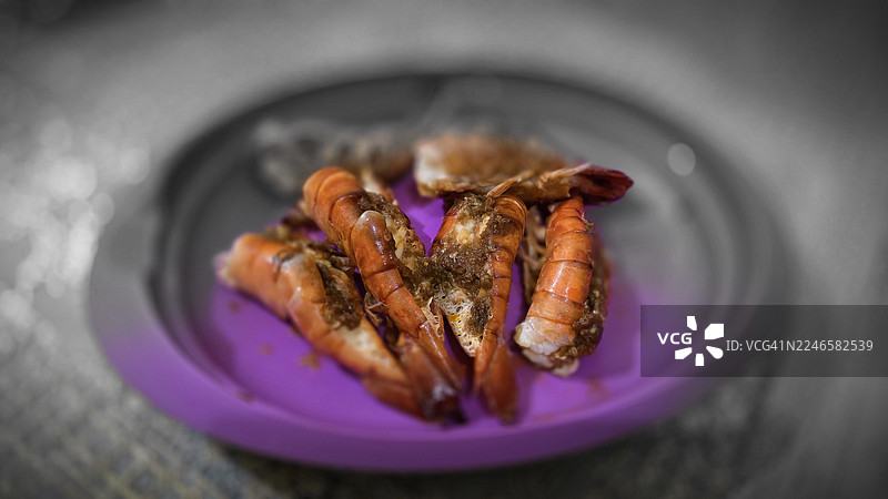 精致调味大虾特写，摆放在色彩鲜艳的紫色盘中，诱人可食图片素材