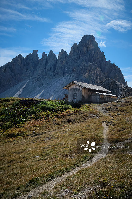 坐落在崎岖高山景观中的乡村山间小屋，背景是蓝天下巍峨的山峰，意大利塞斯托，塞克斯纳多洛米蒂图片素材