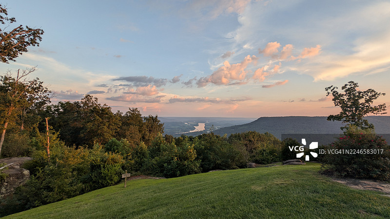 美国马里恩县，生机勃勃的日落天空下，郁郁葱葱的绿色山峦全景，一条蜿蜒的河流穿过图片素材