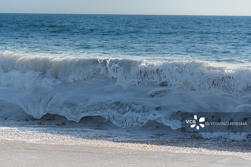 在晴朗的天空下，强大的海浪拍打着沙滩，展现了大自然的原始之美和力量，墨西哥埃尔佩斯卡德罗图片素材
