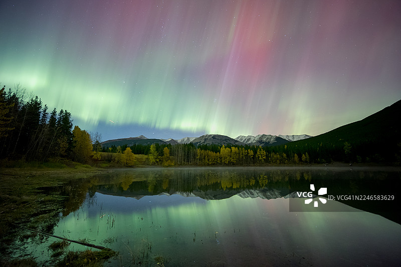加拿大卡纳纳斯基斯村，夜晚，卡纳纳斯基斯，群山与秋季树木映衬在宁静的湖面上，绚丽的北极光倒影图片素材