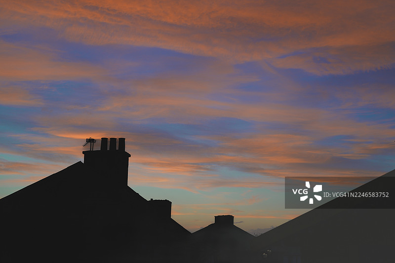 低角度拍摄的建筑屋顶和烟囱的剪影，背景是戏剧性的日落天空，英国巴斯盖特图片素材