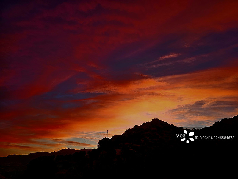西班牙克萨达，戏剧性的多彩日落天空映衬着剪影般的山脉，营造出令人惊叹的自然背景图片素材
