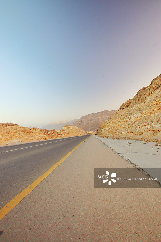 阿曼，萨达街，晴空下的清晰天空，荒漠公路蜿蜒穿过岩石景观图片素材