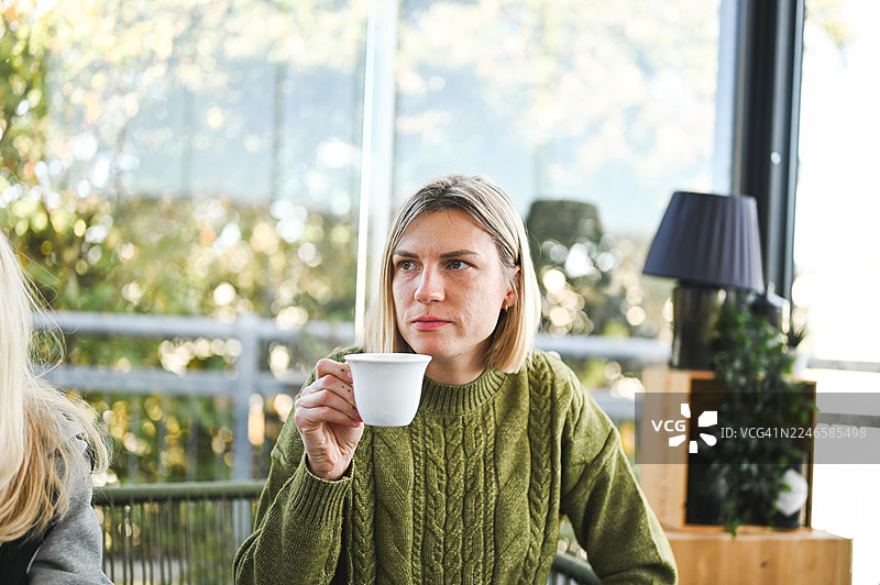 一位女士在咖啡馆里若有所思地喝着咖啡图片素材
