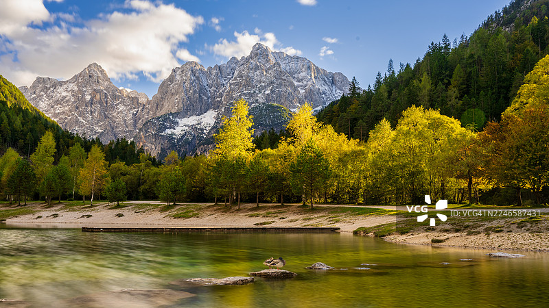 斯洛文尼亚克兰斯卡戈拉，杰尔纳湖，蓝天下的森林和雪山环绕的宁静湖泊景色图片素材