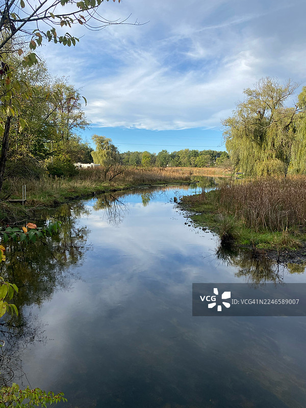 美国维克斯堡，宁静湖面倒映着天空，周围是郁郁葱葱的秋叶美景图片素材
