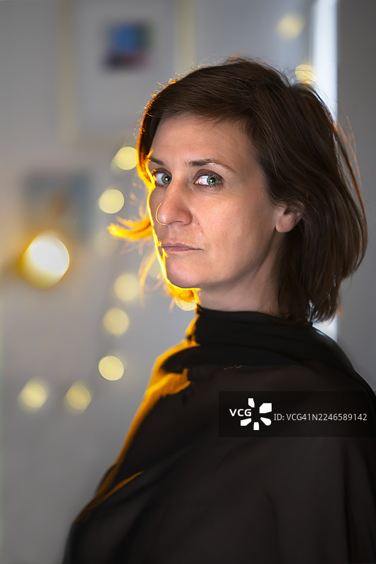 一位女性的特写肖像，她有着迷人的绿色眼睛，在温暖的逆光下回眸图片素材