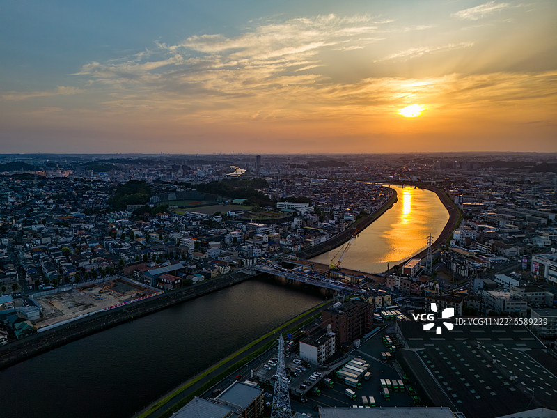 横滨市鹤见区正在进行主要的桥梁更换工程，夕阳倒映在河面上。这是一座横跨河流的桥梁，是无人机拍摄的鹤见川的镜头。该区域西部是横滨市鹤见区，东部是川崎市的川崎区和幸区。图片素材