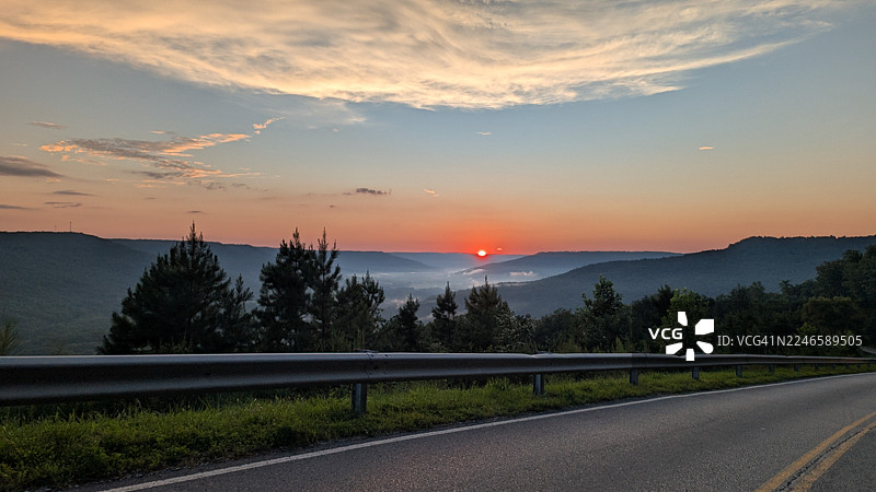 日落时分，树木与天空映衬下的空旷道路，美国马里恩县图片素材