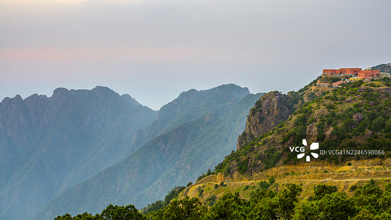 沙特阿拉伯阿卜哈，山顶建筑与朦胧天空下的山景图片素材