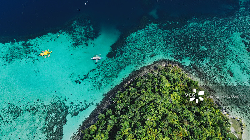 菲律宾马林杜克岛上空俯瞰，郁郁葱葱的绿树和传统船只漂浮在清澈的绿松石般的海水上图片素材