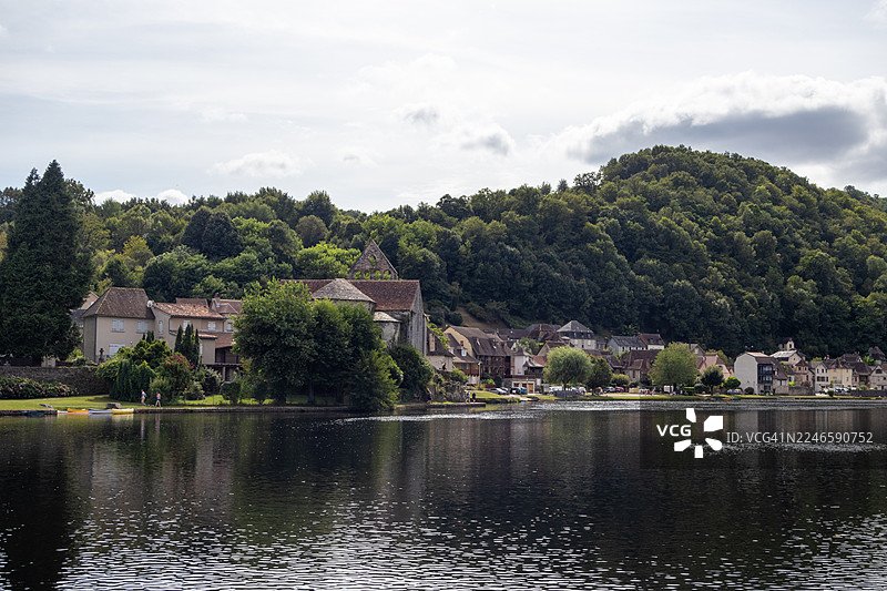 法国康塔尔地区，多云天空下，传统欧洲建筑旁的湖泊风景图片素材
