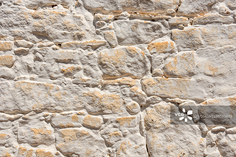 一堵饱经风霜的白色石墙全景，露出天然岩石纹理，营造出质朴的背景图片素材