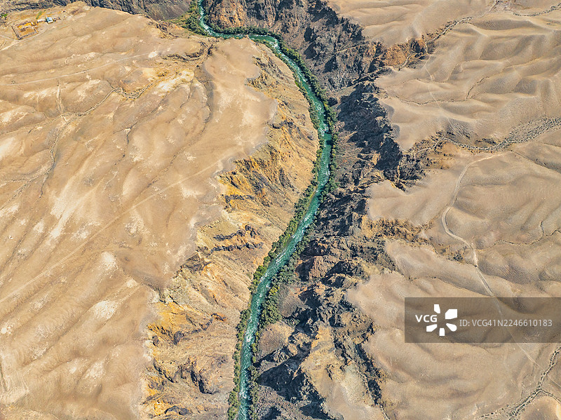 空中俯瞰中亚巨大的查林峡谷，展示了深邃的裂谷切割干旱平原，下方有绿松石色的河流。图片素材