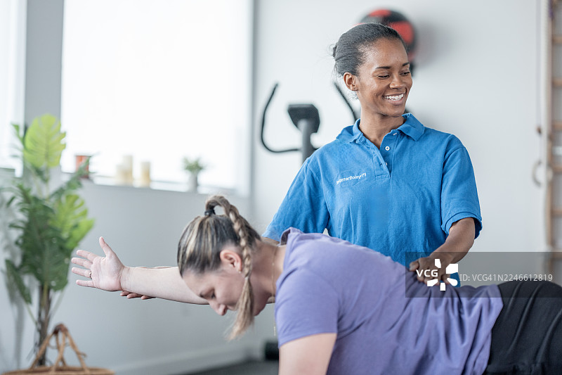 在健身房，专业的非裔女性健身教练指导白人女性进行锻炼图片素材