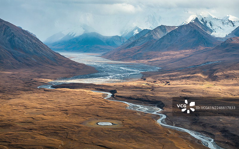 吉尔吉斯斯坦天山山脉高海拔金色高原上，一条蜿蜒的辫状冰川河的壮观鸟瞰图。图片素材