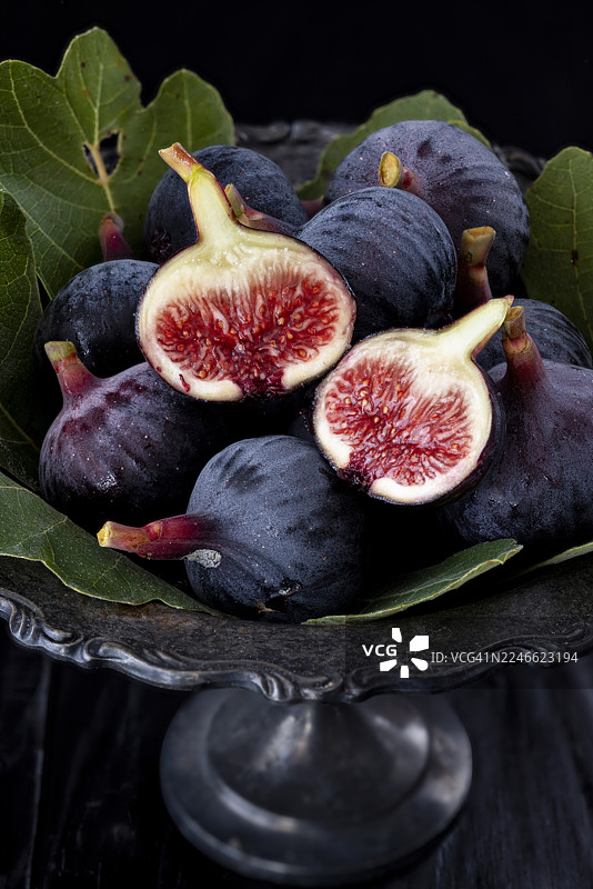 新鲜成熟的无花果放在带叶子的深色碗里图片素材