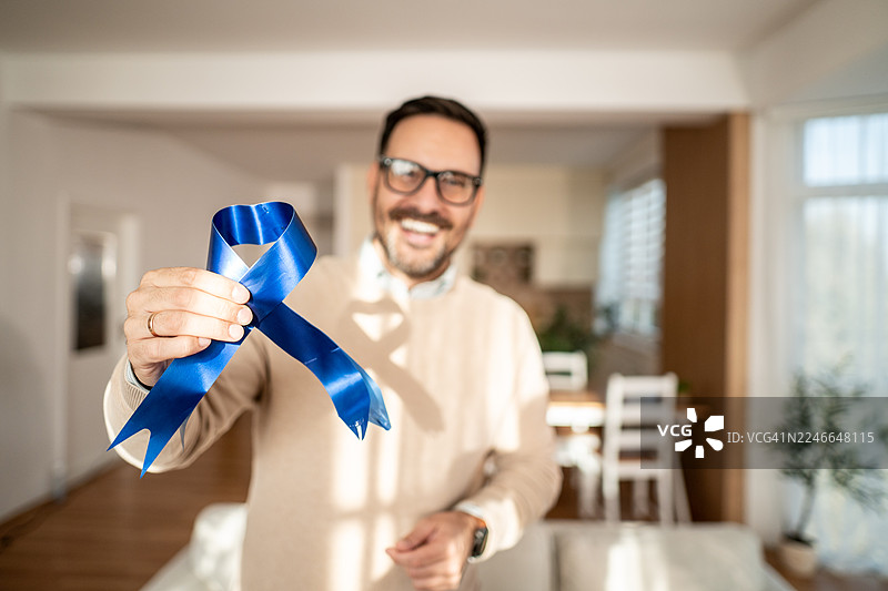 男人手持蓝色丝带，支持前列腺癌防治宣传图片素材