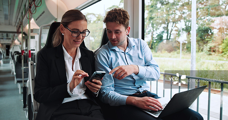 火车上的人们讨论金融项目，进行商务旅行。笔记本电脑、手机和金融经理与顾问在公共交通工具上讨论投资提案。图片素材