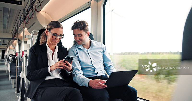火车上，科技、商务人士快乐地讨论金融项目，为出行做准备。在公共交通工具上，一位金融经理与顾问一起查看笔记本电脑和手机，讨论投资提案。图片素材