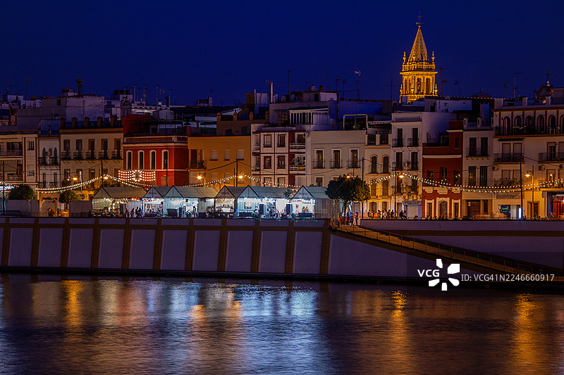 西班牙塞维利亚特里亚纳区景观，节日集市小屋和灯火辉煌的圣安娜教堂塔楼——圣安娜节，2024年7月21日图片素材