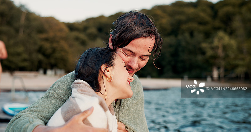 假期里，人们在湖边放松、拥抱，并用毛巾互相依偎，寻求舒适、支持或增进感情。在夏日假期、短途旅行或周末出游时，快乐相爱的男人在河边拥抱着女人取暖。图片素材