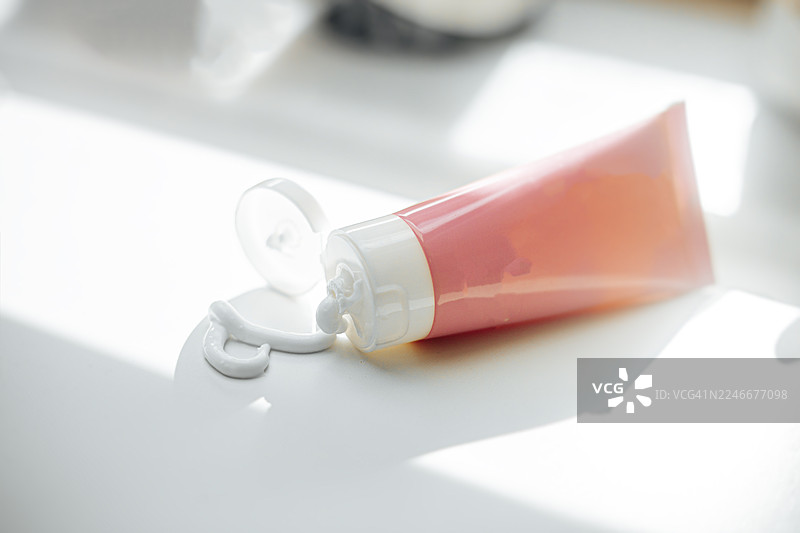 一个无品牌的粉色管状物，外观像奶油或牙膏产品，管口挤出少量产品。该图像具有干净、简约和概念性的美学，着重于纹理、色彩和形式。管子的设计简单，使其具有通用性图片素材