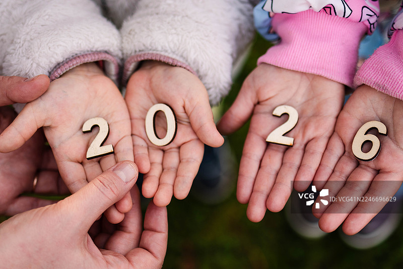 孩子拿着木制的数字2026，有父母的手在支撑图片素材