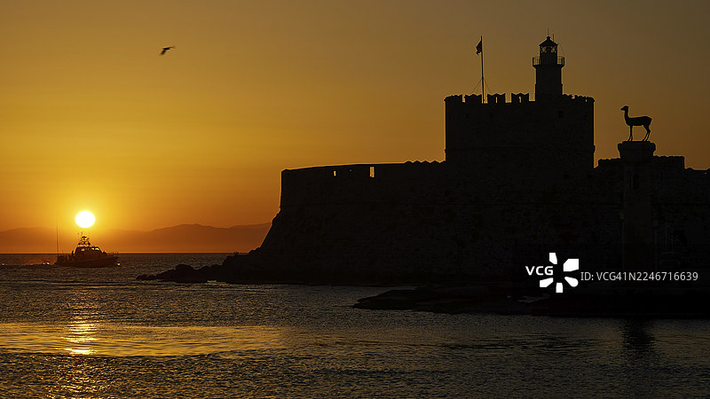 Agios Nikolaos 教堂，日出时分的海景，伴有城堡剪影和一艘过往的船只，联合国教科文组织世界遗产，罗德镇老城，罗德岛，佐泽卡尼撒群岛，希腊图片素材