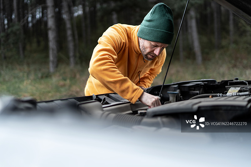 男人在森林里检查汽车发动机故障图片素材