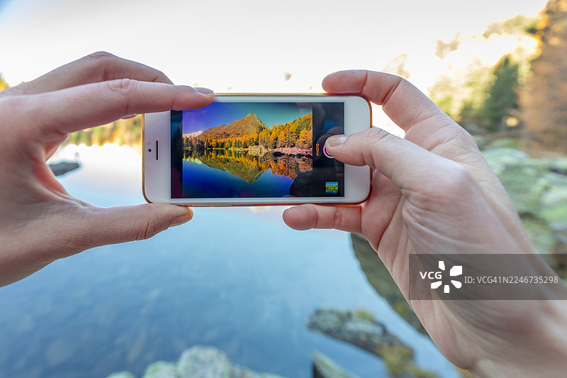 特写：智能手机正在拍摄瑞士格劳宾登州波斯基亚沃的Saoseo湖，位于瓦尔迪坎波图片素材