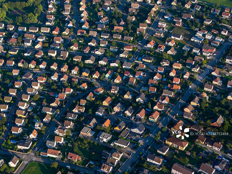 俯瞰住宅区，房屋众多，绿地环绕，沐浴在自然光下图片素材