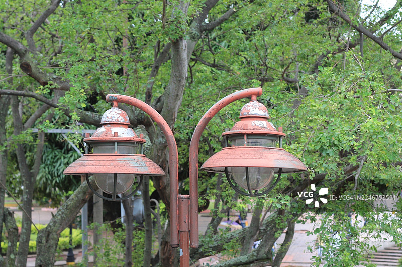 特写镜头，两盏褪色的老式路灯，背景是郁郁葱葱的绿树，哥伦比亚卡利图片素材