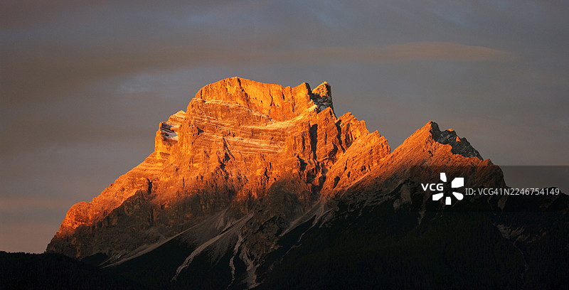 夕阳余晖沐浴下的雄伟山峰，崎岖的岩石构造在戏剧性的天空背景下展露无遗，意大利圣维托迪卡多雷图片素材