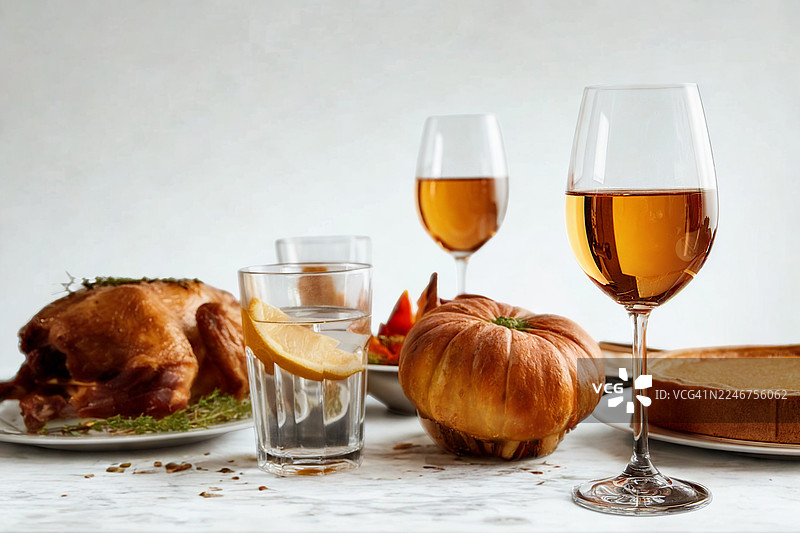 美味的感恩节或圣诞节晚餐，节日餐桌上摆放着烤火鸡、南瓜和葡萄酒。图片素材