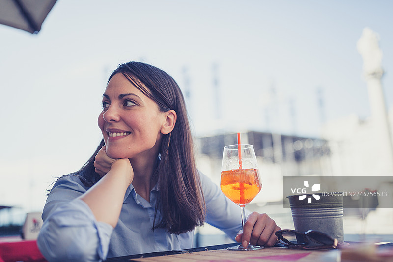 面带微笑的女士在户外咖啡馆享用鸡尾酒图片素材