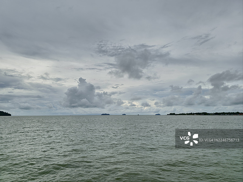 远方岛屿在地平线上，戏剧性的多云天空映衬着海景图片素材