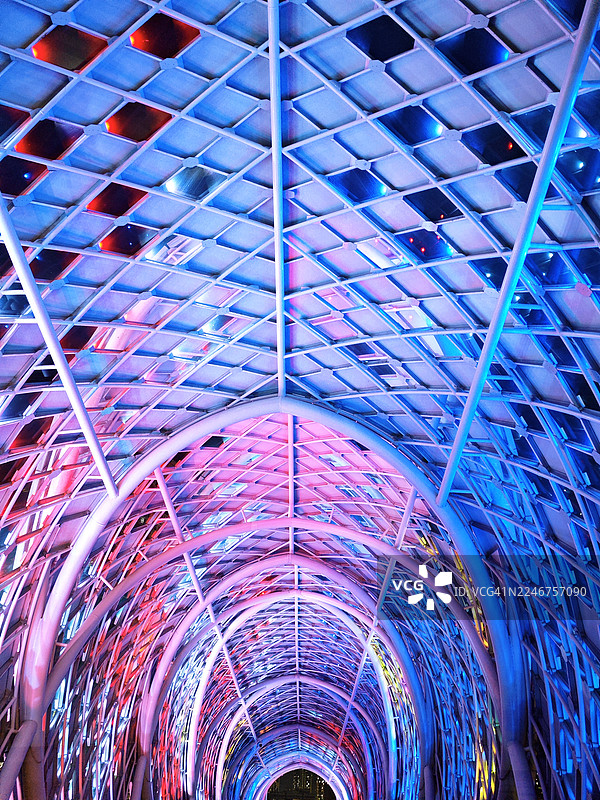 马来西亚夜晚，充满活力的灯光照射下的现代建筑隧道，带有几何图案和多彩灯光图片素材