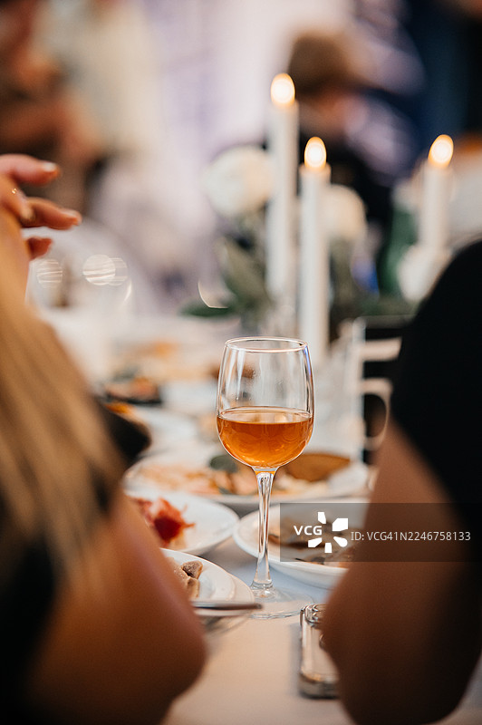 餐厅餐桌上的酒杯，背景是模糊的人群和蜡烛图片素材