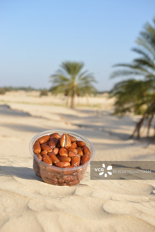 塑料盒装的新鲜椰枣，背景是沙漠和棕榈树图片素材